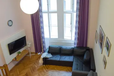 a living room with a black leather couch and a large window at Apartment Jindrisska 25 in Prague