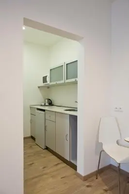 a kitchen with white cabinets and a white chair at Rozmaryn Rooms & Apartments in Rakovník