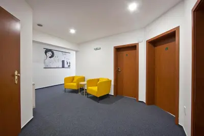 a waiting room with yellow chairs and a table at Rozmaryn Rooms & Apartments in Rakovník