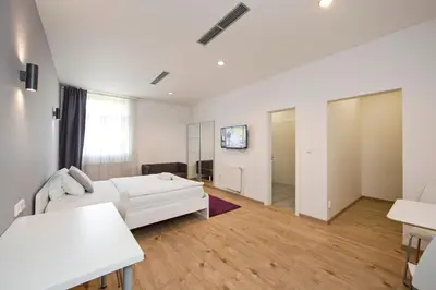 a white living room with a couch and a table at Rozmaryn Rooms & Apartments in Rakovník