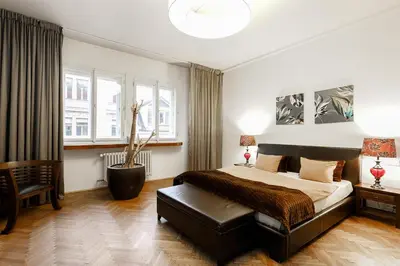 a bedroom with a bed and a chair and windows at LUXURY Apartment Dlouha in Prague
