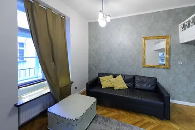 a living room with a black couch and a window at Pinkova Apartments in Prague
