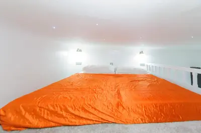 an orange bed in a white room with two pillows at Pinkova Apartments in Prague