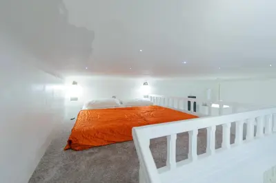 a white room with a bed with an orange blanket at Pinkova Apartments in Prague