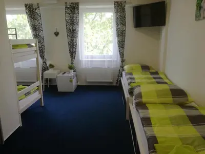 two beds in a room with a window at Sporthotel Zimní stadion Benešov in Benešov