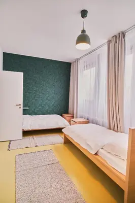 a bedroom with two beds and a green wall at Hostel Prazacka in Prague