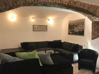 a living room with a black couch and a brick wall at Big Homebase with Billardtable in Prague