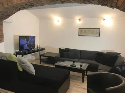 a living room with a black couch and a tv at Big Homebase with Billardtable in Prague