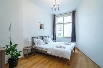 a white bedroom with a bed and a window at Royal Road Residence in Prague