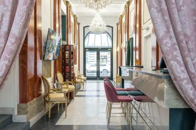 a room with a bar with chairs and a chandelier at Hotel Praga 1885 by Wagnerstays in Prague