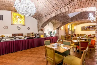 a restaurant with wooden tables and chairs and a chandelier at Hotel Caruso Old Town in Prague