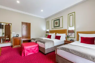 a hotel room with two beds and a pink stool at Hotel Caruso Old Town in Prague