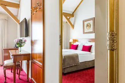 a bedroom with a bed and a desk and a mirror at Hotel Caruso Old Town in Prague