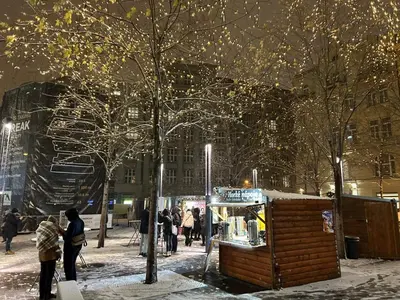 a group of people standing around a food stand in the snow at Hostel Downtown in Prague