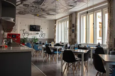 a dining room with tables and chairs and windows at Hostel Downtown in Prague