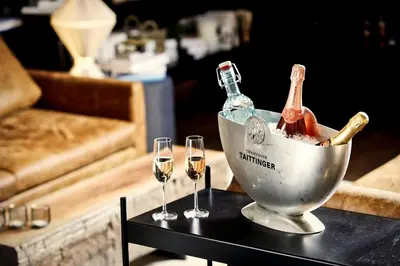 two wine glasses and a bucket with wine bottles in it at MOSAIC HOUSE Design Hotel in Prague