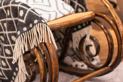 a wooden rocking chair with a blanket on it at MOSAIC HOUSE Design Hotel in Prague