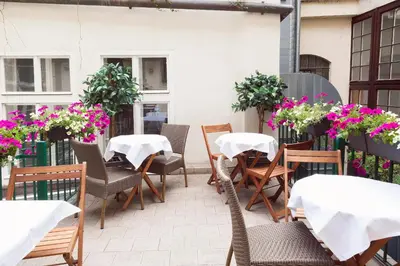 an outdoor patio with tables and chairs and flowers at Old Town Square Residence by Emblem in Prague