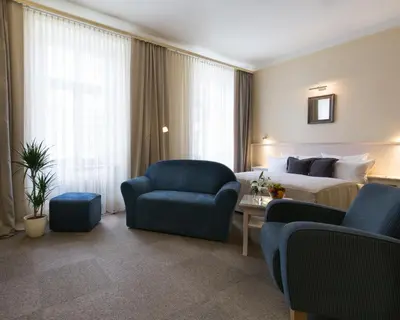 a hotel room with a bed and a couch and chairs at Unitas Hotel in Prague