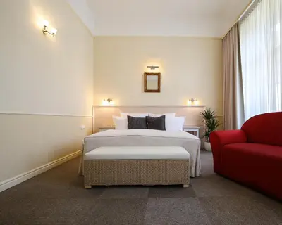 a hotel room with a bed and a red couch at Unitas Hotel in Prague