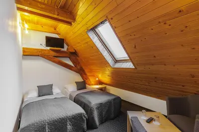 a attic room with two beds and a window at Hotel BELLA in Prague