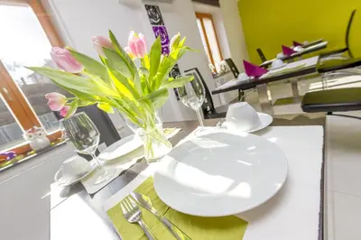a table with a white plate and flowers in a vase at Hotel Herrmes in Prague