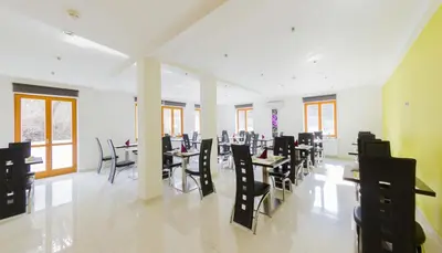 a dining room with tables and chairs and windows at Hotel Herrmes in Prague