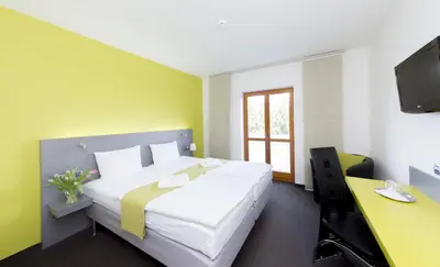 a bedroom with a bed and a desk and a tv at Hotel Herrmes in Prague