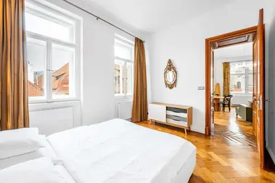 a white bedroom with a bed and a window at Malostranská Residence in Prague