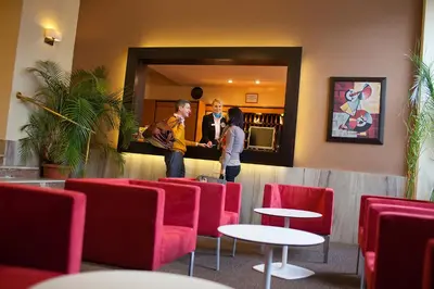 a group of people standing in a restaurant with red chairs at Hotel Merkur - Czech Leading Hotels in Prague