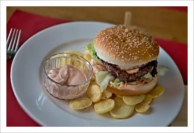 a white plate with a hamburger and chips and dip at Motel U Krbu in Vestec