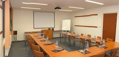 a classroom with long tables and chairs and a whiteboard at Hotel S-centrum in Benešov