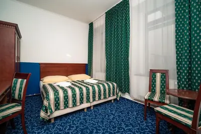 a bedroom with a bed and two chairs and a table at Hotel Czechia in Prague
