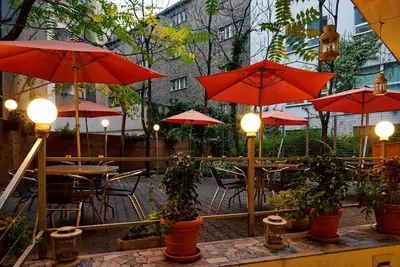 a patio with red umbrellas and tables and chairs at Hotel Ankora in Prague