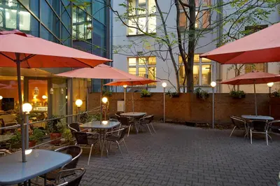 a patio with tables and chairs with red umbrellas at Hotel Ankora in Prague