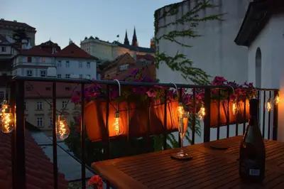 a wooden table on a balcony with lights on it at Apartman Mala Strana -Piece and quiet in Prague