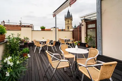 a balcony with tables and chairs and a clock tower at Hotel Dar in Prague