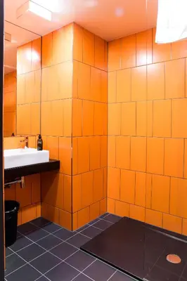 an orange tiled bathroom with a sink and a mirror at MeetMe23 in Prague