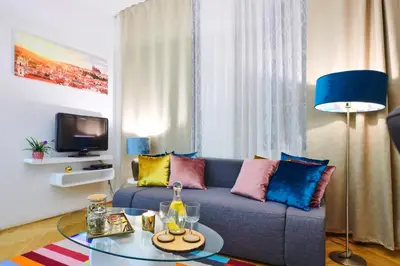 a living room with a blue couch with colorful pillows at Royal Route Residence in Prague