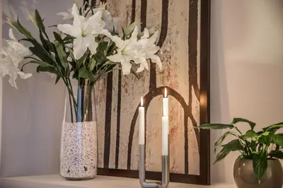 a candle and two vases with white flowers on a shelf at Royal Route Residence in Prague