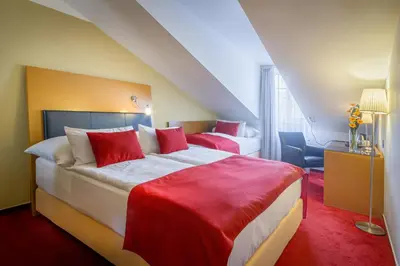 a bedroom with a large bed with red sheets at Theatrino Hotel in Prague