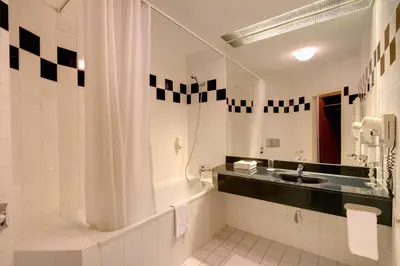 a bathroom with a tub and a sink and a mirror at Theatrino Hotel in Prague