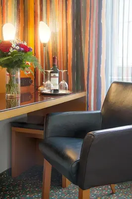 a desk with a bottle of wine and a chair at Theatrino Hotel in Prague