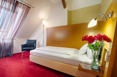 a hotel room with a bed and a vase of red flowers at Theatrino Hotel in Prague