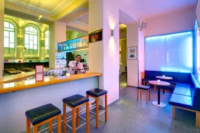 a woman sitting at a bar in a restaurant at Theatrino Hotel in Prague