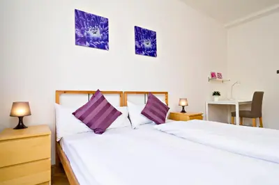a bedroom with two white beds with purple pillows at Apartments with 2 Bathrooms in Prague