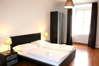 a bedroom with a bed with white sheets and a window at Betlem Prague Apartments in Prague