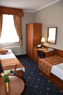 a hotel room with two beds and a desk at Arbes in Prague