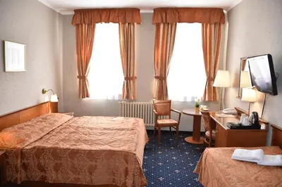 a hotel room with two beds and a desk at Arbes in Prague