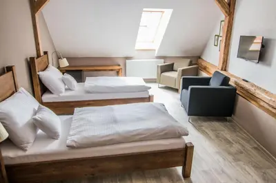 a large room with two beds and a chair at Pension Viktorin in Poděbrady